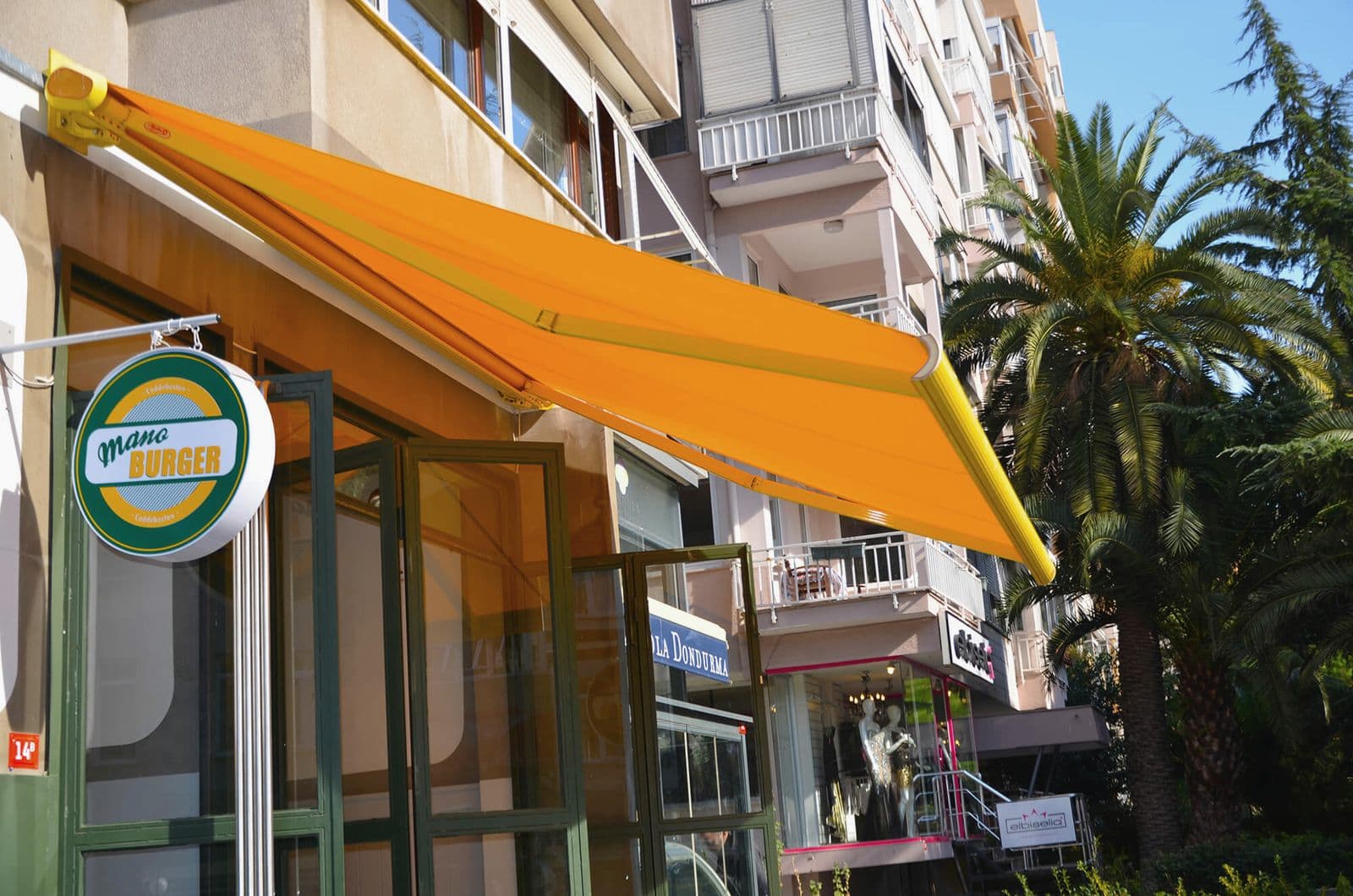 Burger restoranı cephesinde açık turuncu kumaşlı kasetli tente