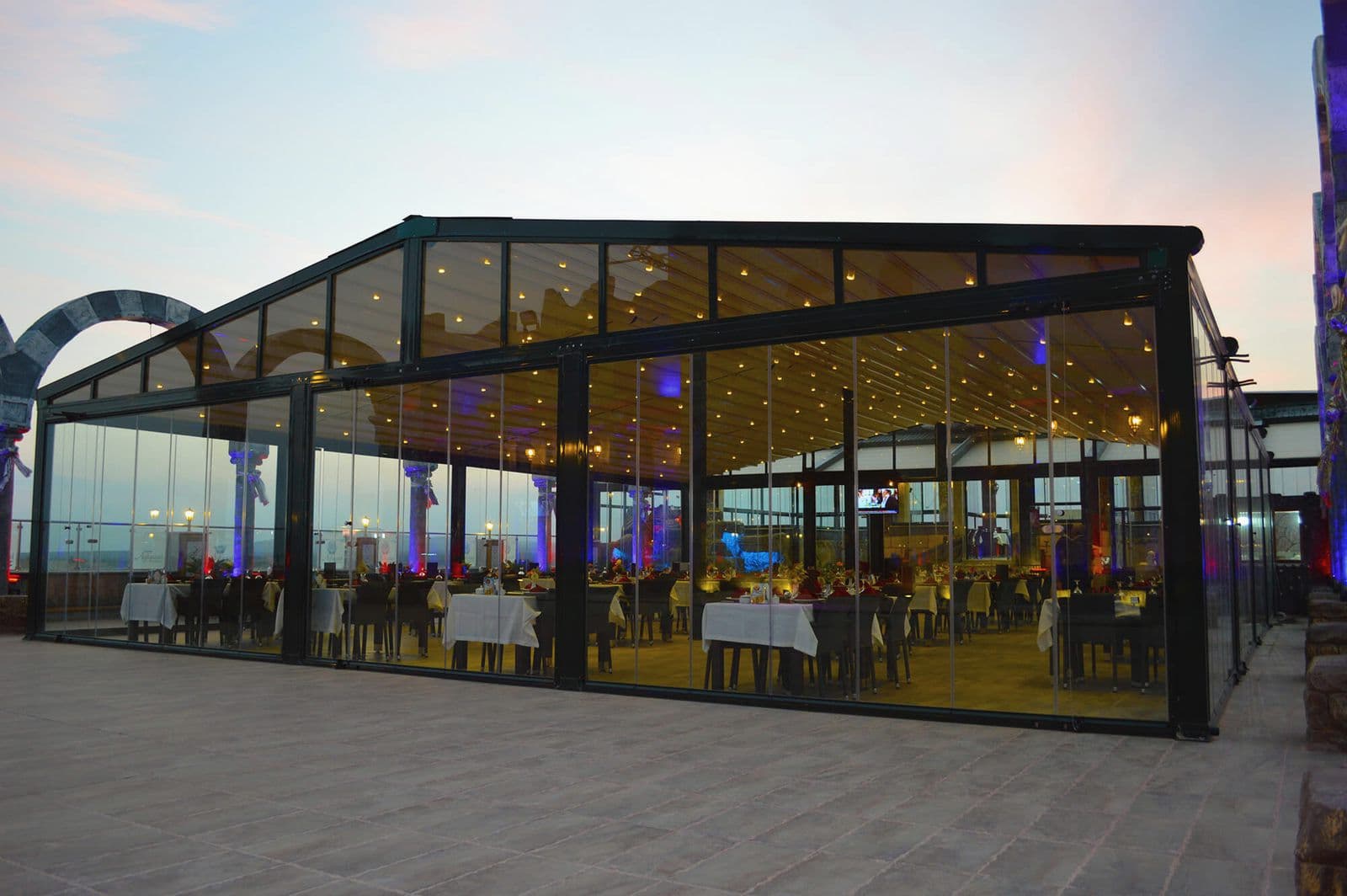 Akşam saatinde pergole ve cam sistemle kapatılmış restoran terası