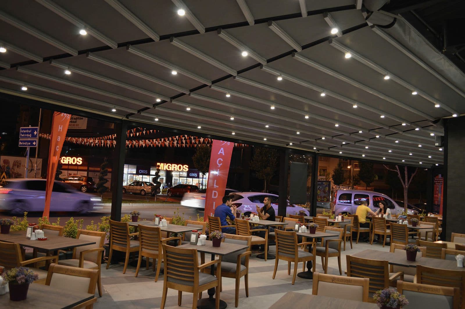 Gece LED spotlarla aydınlatılmış alüminyum pergole altında restoran terası