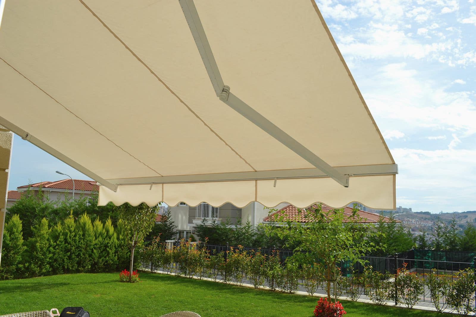 Bahçe çimeninin üzerine açılmış krem renkli mafsallı tente